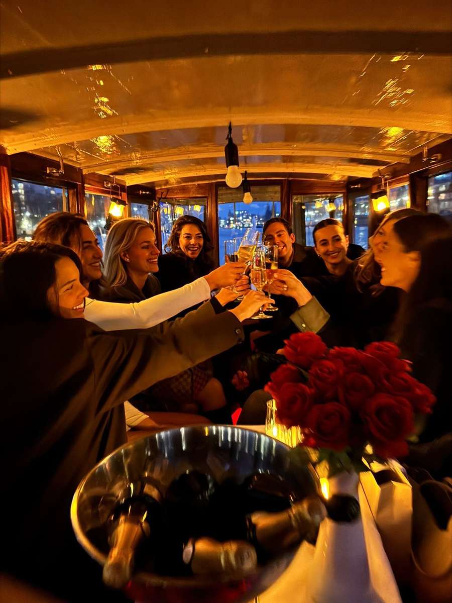 Private group raising glasses aboard salon boat Energie at night